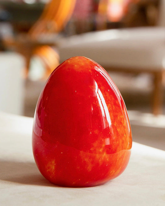 Glossy red egg-shaped object on a blurred indoor background