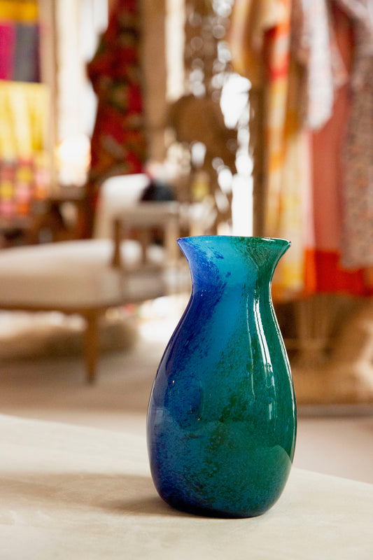 Blue glass vase on a table with a blurred indoor background