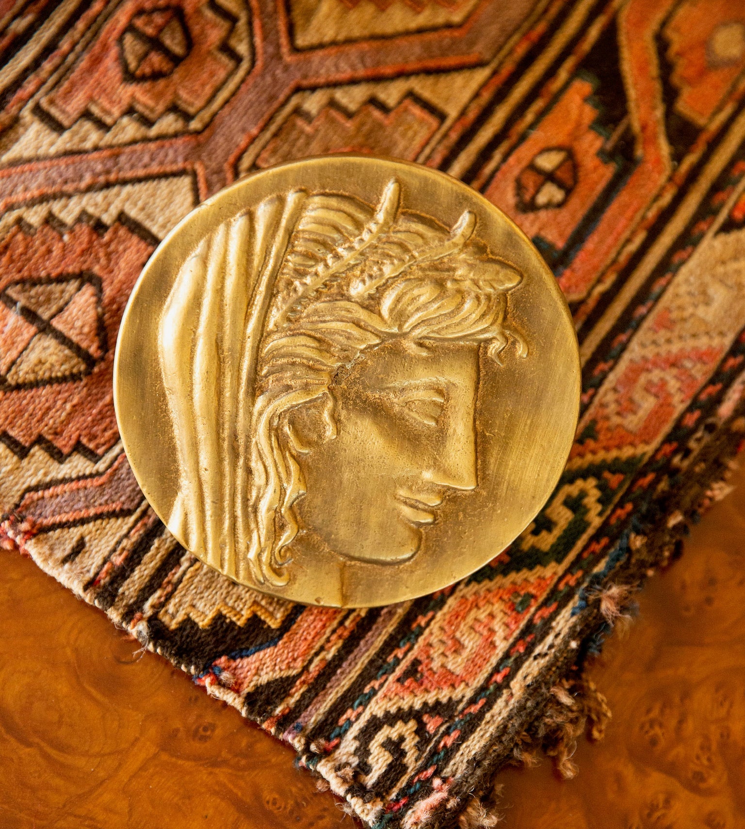 Gold coin with a face design on an ornate rug
