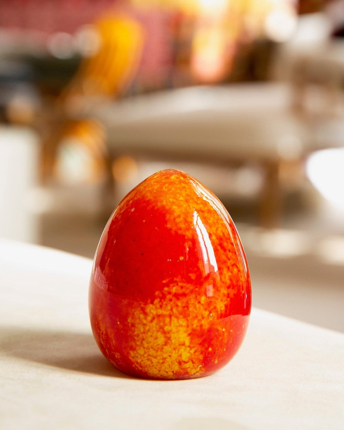 Red and orange speckled egg on a white surface with blurred background