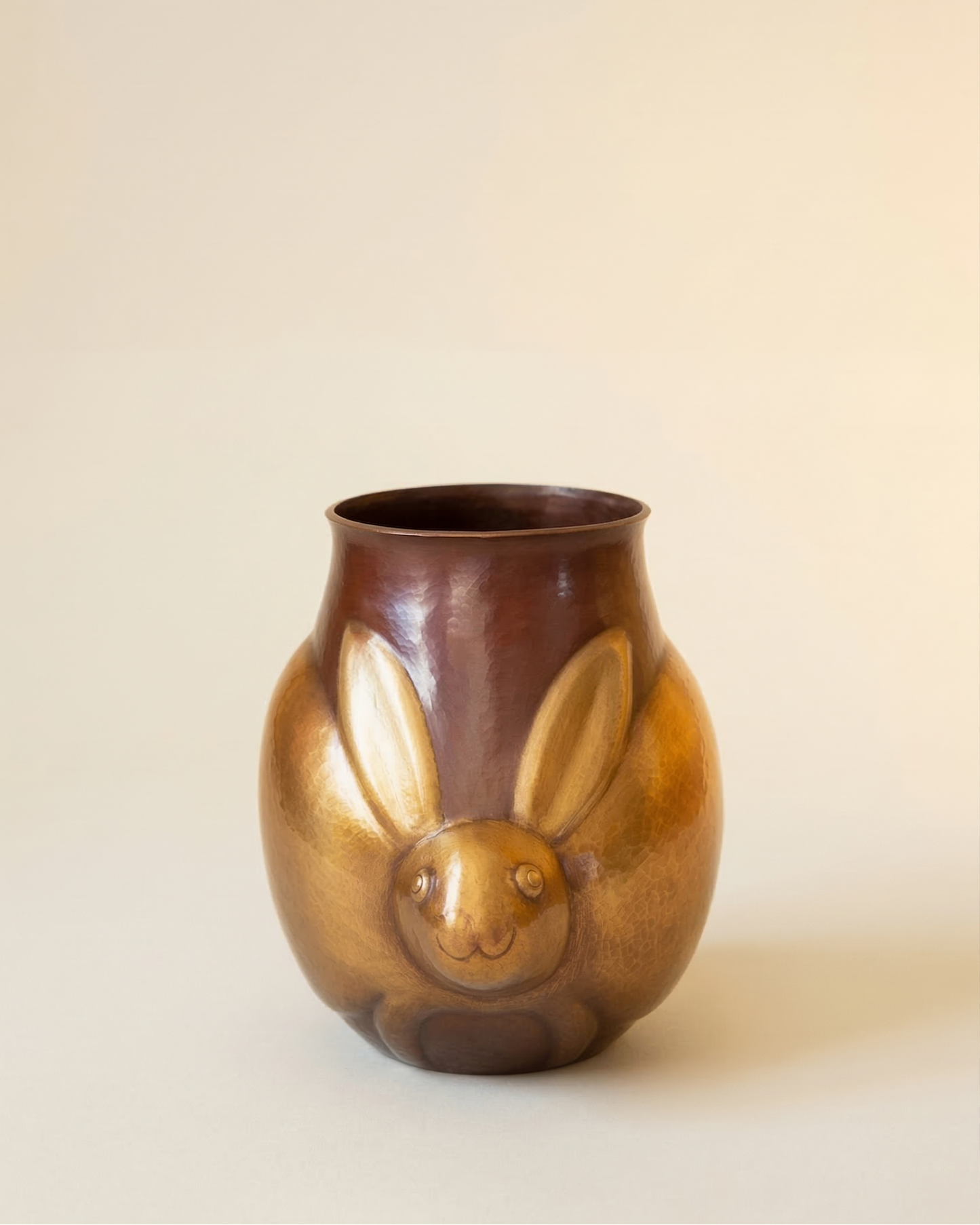 Brown ceramic vase with a rabbit face design on a beige background