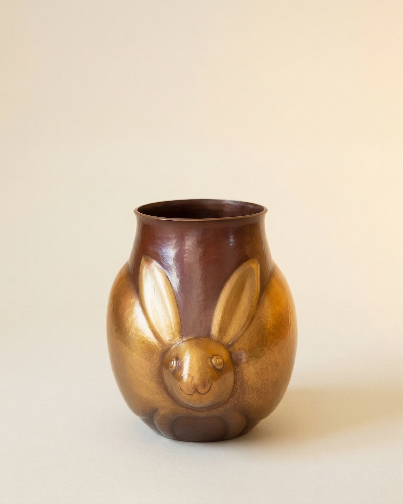 Brown ceramic vase with a rabbit face design on a beige background